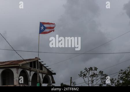 Naguabo, USA. August 2024. Eine Puerto-ricanische Flagge, die am 14. August 2024 über einem verlassenen Haus in Naguabo, Puerto Rico, fliegt. Präsident Biden genehmigte eine Notstandserklärung für Puerto Rico am späten Dienstagabend. Mehr als 700.000 Kunden verloren durch den Sturm Strom. Quelle: SIPA USA/Alamy Live News Stockfoto