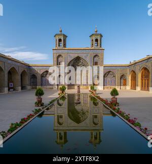 Shiraz, Iran – 5. Mai 2019: Iranische Frau im Innenhof mit Pool der Nasir al-Mulk-Moschee. Die Nasir Al-Mulk Moschee ist auch bekannt als Pink Mosque. Stockfoto