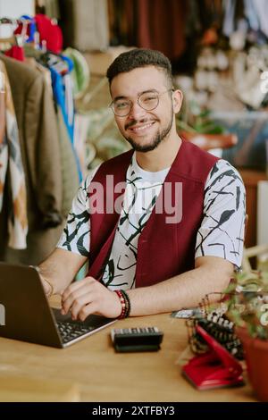 Porträt eines lächelnden Mannes, der im Büro an einem Laptop arbeitet Stockfoto