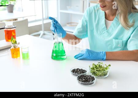Glückliche Wissenschaftlerin mit Sonnenblumenkernen und Sprossen, die im Labor arbeiten, Nahaufnahme Stockfoto