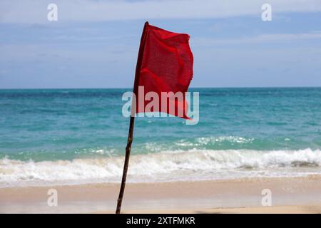 Rote Warnfahne auf dem Hintergrund eines Meeresstrandes. Schild, das darauf hinweist, dass Schwimmen verboten ist Stockfoto