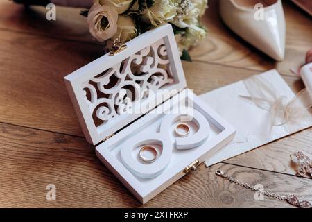 Brautjungfernkostüme: Absatzschuhe, Blumenstrauß, Ringe, Parfüm und Einladung auf dem Tisch Stockfoto