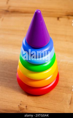 Regenbogenplastik-Stapelturm-Spielzeug für Kleinkinder auf Holzoberfläche Stockfoto