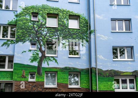 Wohnhäuser an der Feldsieper Straße in Bochum, nach einer energetischen Sanierung, mit Fassadendämmung, hat die Bochumer Wohnstätten Wohnungsgenossenschaft, die Gebäude mit einem großen Wandbild bemalen lassen, vom Dortmunder Graffiti Künstler Denis Klatt, es zeigt auf der gesamten Fassade ein Blaukehlchen und eine Landschaft mit Bäumen, Leben unter der Erde und viel Himmel, Bochum-Hamme, NRW, Deutschland, Wandbild *** Wohnhäuser an der Feldsieper Straße in Bochum, nach einer energetischen Sanierung, mit Fassadendämmung, hat die Bochumer Wohnstätten Wohnungsgenossenschaft den Bau veranlasst Stockfoto