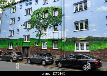 Wohnhäuser an der Feldsieper Straße in Bochum, nach einer energetischen Sanierung, mit Fassadendämmung, hat die Bochumer Wohnstätten Wohnungsgenossenschaft, die Gebäude mit einem großen Wandbild bemalen lassen, vom Dortmunder Graffiti Künstler Denis Klatt, es zeigt auf der gesamten Fassade ein Blaukehlchen und eine Landschaft mit Bäumen, Leben unter der Erde und viel Himmel, Bochum-Hamme, NRW, Deutschland, Wandbild *** Wohnhäuser an der Feldsieper Straße in Bochum, nach einer energetischen Sanierung, mit Fassadendämmung, hat die Bochumer Wohnstätten Wohnungsgenossenschaft den Bau veranlasst Stockfoto