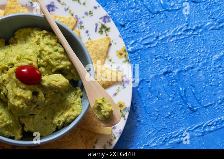 Guacamole mit Kirschtomaten oben umgeben von Nachos, die von oben nach unten fotografiert wurden. Stockfoto