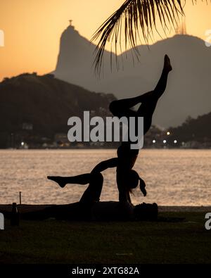 Eine Silhouette von zwei Personen, die Akro-Yoga bei Sonnenuntergang üben Stockfoto
