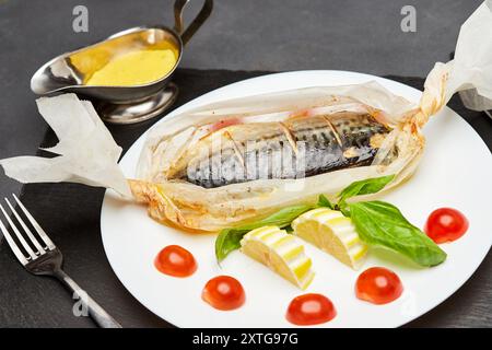 Gourmet gebackene Makrele in Pergament mit Zitronenscheiben, Basilikum und Kirschtomaten Stockfoto