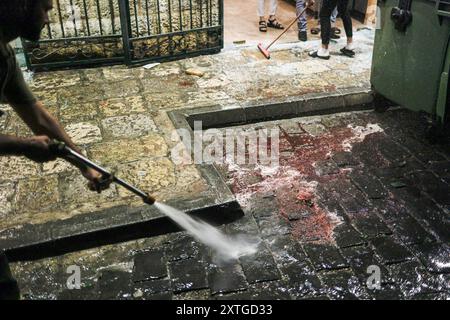 Marjayoun, Libanon. August 2024. (ANMERKUNG DER REDAKTION: Bild enthält Grafikinhalte) Ein Zivilist räumt den Ort auf, an dem die beiden Hisbollah-Soldaten in Marjayoun angegriffen wurden. Mindestens zwei Menschen wurden bei einem Drohnenangriff im Südlibanon getötet und vier verletzt. Quelle: SOPA Images Limited/Alamy Live News Stockfoto