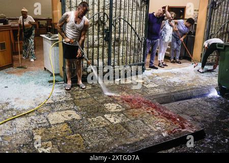 Marjayoun, Libanon. August 2024. (ANMERKUNG DER REDAKTION: Bild enthält Grafikinhalte) Ein Zivilist räumt den Ort auf, an dem die beiden Hisbollah-Soldaten in Marjayoun angegriffen wurden. Mindestens zwei Menschen wurden bei einem Drohnenangriff im Südlibanon getötet und vier verletzt. Quelle: SOPA Images Limited/Alamy Live News Stockfoto