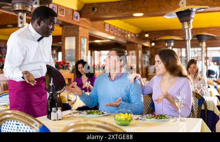 Unzufriedener Gast, der mit dem Kellner in Konflikt steht Stockfoto