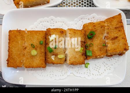 Rübenkuchen oder Rettichkuchen werden als Teil von Dim Sum auf einem Tisch in einem Restaurant in George Town, Penang, Malaysia serviert. Stockfoto