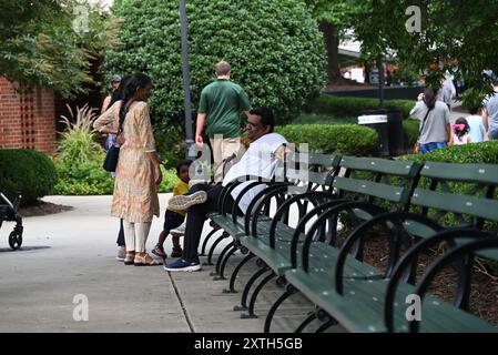 Eine Familie, die sich auf den öffentlichen Bänken in Pullen Park, Raleigh NC, ausruhen lässt. Stockfoto