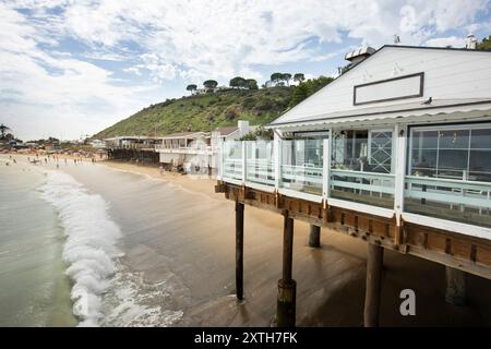 Malibu, Kalifornien, USA - 9. September 2023: Am Nachmittag scheint Sonnenlicht auf dem historischen Malibu Pier, als Wellen am Carbon Beach abstürzen. Stockfoto