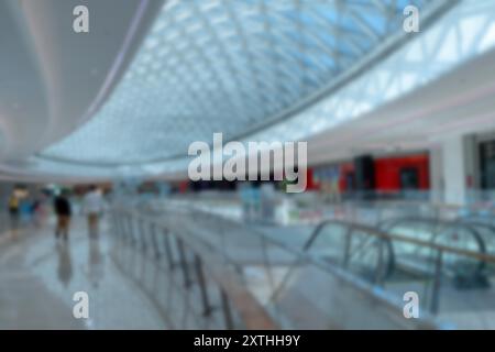 Verschwommenes Interieur eines modernen Einkaufszentrums mit Glasdecke und Rolltreppen. Stockfoto