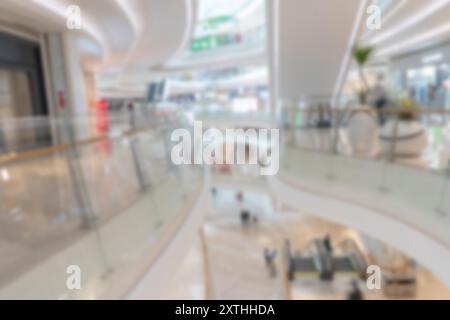 Verschwommener Blick auf ein modernes Einkaufszentrum mit zentralem Atrium und Rolltreppen, was Bokeh-Effekt erzeugt. Stockfoto