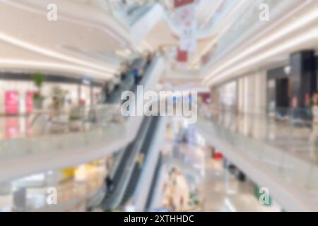 Ein verschwommenes Bild eines modernen Einkaufszentrums in Shenzhen, China, mit Rolltreppen und Bokeh-Lichtern. Stockfoto