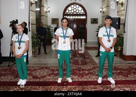 Algier, Algerien. August 2024. Der algerische Präsident Abdelmadjid Tebboune erhält Goldmedaillengewinner Imane Khelif (Mitte) sowie die beiden anderen Olympiasieger Djamel Sedjati (rechts) und Kaylia Nemour (links) im Mouradia Presidential Palace in Algier (Algerien) am 14. August 2024. Foto: Balkis Press/ABACAPRESS. COM Credit: Abaca Press/Alamy Live News Stockfoto