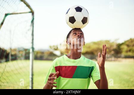 Sport, Junge und Ball auf dem Kopf mit Fußball auf dem Feld für Balance, Trickübungen und Training für Wettkämpfe. Fußballspieler, Person und Spiel Stockfoto