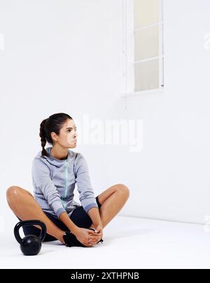 Fitness, Stretching und Denken mit der Frau auf der Etage des Studios für den Beginn der Herausforderung oder Leistung. Bewegung, Idee und Kettlebell mit Sportperson Stockfoto