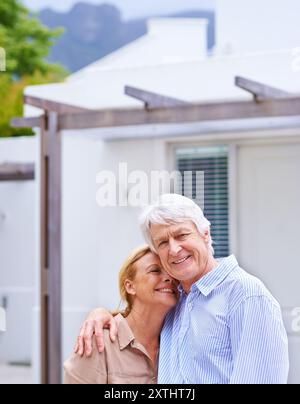 Seniorenpaar, Umarmungen und Immobilien im Freien für Investitionen, Hypotheken oder Darlehen für einen neuen Heim-Traum. Ruhestand, Mann und glückliche Frau durch Immobilienverkauf für Stockfoto