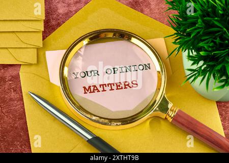 Textschild, das IHRE MEINUNG durch eine Lupe in einem aus einem Umschlag hervorgehenden Brief zeigt Stockfoto