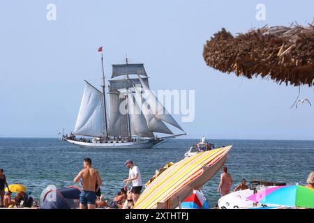 Blick am Mittwoch 14.08.2024 im Ostseebad Warnemünde, ein Ortsteil der Hanse- und Universitätsstadt Rostock, bei sommerlichem Wetter auf den örtlichen Strand mit dem Segelschiff Tolkien im Mittelpunkt. In den Urlaubsorten entlang der Ostseeküste des Landes Mecklenburg Vorpommern herrscht derzeit reges Treiben. In direkter Strandnähe ist fast kein freier Platz mehr zu finden und die Restaurants sind gut besucht. Dennoch bleibt ein Wermutstropfen. Die Preise in den Tourismusregionen des Landes MV sind in diesem Jahr noch einmal gestiegen. Das hält zahlreiche Menschen aber nicht davon ab, die B Stockfoto