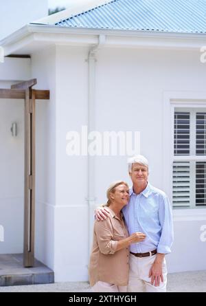 Seniorenpaar, Umarmung und neues Zuhause im Freien für Traumimmobilieninvestitionen, Hypotheken oder Kredite. Ruhestand, Mann und glückliche Frau durch Immobilienverkauf für Stockfoto