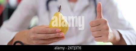 Arzt mit gelber Birne und Daumen-hoch-Zeichen Stockfoto