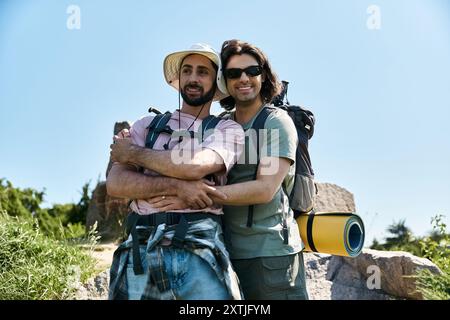 Ein junges schwules Paar wandert an einem sonnigen Sommertag gemeinsam durch die Natur, ihr Lächeln und ihre Umarmung zeigen ihre Liebe und ihr Glück. Stockfoto