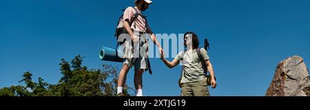 Ein junges schwules Paar wandert zusammen in einer sonnigen Wildnis. Stockfoto