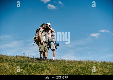 Ein junges schwules Paar wandert gemeinsam in die Wildnis und macht eine Pause, um die Aussicht an einem sonnigen Sommertag zu genießen. Stockfoto