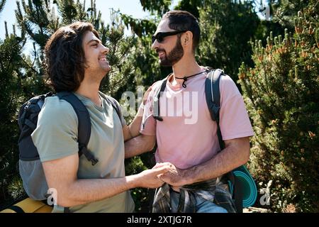 Ein junges schwules Paar macht eine Wanderung in der Natur, lächelt und hält Hände, während es die Wildnis erkundet. Stockfoto