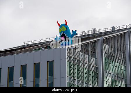 Slough, Großbritannien. August 2024. Das Stadtzentrum von Slough in Berkshire sah heute fröhlicher aus als sonst, als fünf riesige aufblasbare Dachmonster die Käufer und Besucher des Stadtzentrums begrüßten. Die Künstler Luke Egan und Peter Hamilton haben die riesigen aufblasbaren Monster auf dem Porter Building, dem Queensmere Shopping Centre, The Future Works, Aston Bond Solicitors und dem Brickhouse installiert. Monster Nosey Bonk, Bezerker, Tentakel, Brülzer und eine Familie von Goofs erweisen sich in den Schulferien als großer Hit bei Kindern. Die Monster bleiben in dir Stockfoto