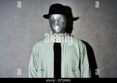 Mystery man in Hut mit Klebeband Gesichtspflege auf grauem Hintergrund. Horror, Geheimnis und Inkognito Konzept Stockfoto