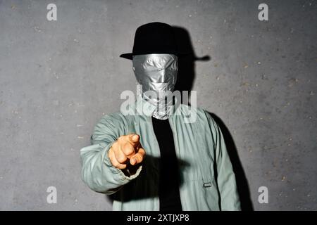 Mystery man mit Klebeband Gesicht, der seinen Finger auf dich zeigt und Kamera über grauem Hintergrund Stockfoto