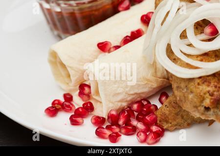Traditioneller gegrillter Kebab mit Granatapfel, Zwiebeln und scharfer Sauce für ein köstliches kulinarisches Erlebnis Stockfoto