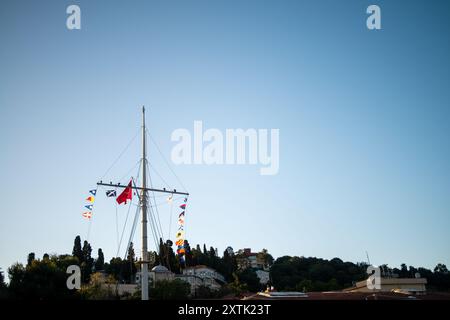 Eine lebendige Darstellung von Meeresflaggen, die jeweils unterschiedliche Signale und Botschaften in der nautischen Kommunikation repräsentieren und gegen einen klaren blauen Himmel flattern. Stockfoto