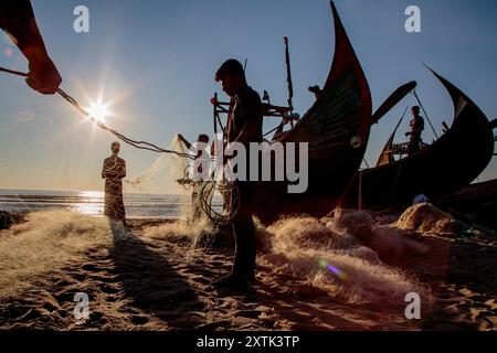 Die Fischer bereiten die Fischernetze vor der nächsten Flut vor. Die mondförmigen Fischerboote sind einzigartig für das Gebiet in der Nähe von Cox's Bazar in Bangladesch. Stockfoto