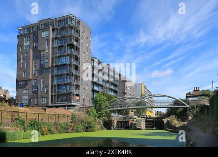 Stahlsteg über den Regents Canal am Salmon Lane Lock, East London. Lascar Wharf Wohnsiedlung dahinter. Stockfoto