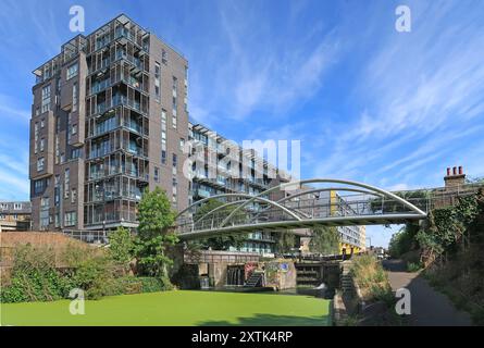 Stahlsteg über den Regents Canal am Salmon Lane Lock, East London. Lascar Wharf Wohnsiedlung dahinter. Stockfoto