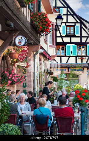 ALSACE KAYSERSBERG im Freien Besuchertische Restaurant Kellnerin Mittagessen und Weinprobe im belebten Caveau du Schlossberg Kaysersberg Elsass Frankreich Stockfoto