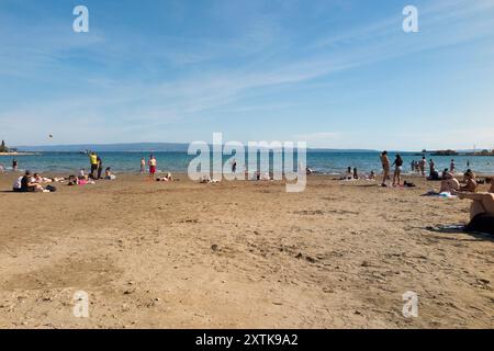 Sandiger, schöner Touristenstrand, der von Einheimischen und Touristen an einem heißen, sonnigen Tag mit blauem Himmel und Sonne genossen wird. Strand von Bacvice. Trennen. Kroatien. (138) Stockfoto