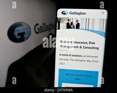 Person, die ein Smartphone hält und die Webseite des US-Versicherungsunternehmens Arthur J. Gallagher Co. (AJG) vor dem Logo zeigt. Konzentrieren Sie sich auf die Mitte des Telefondisplays. Stockfoto