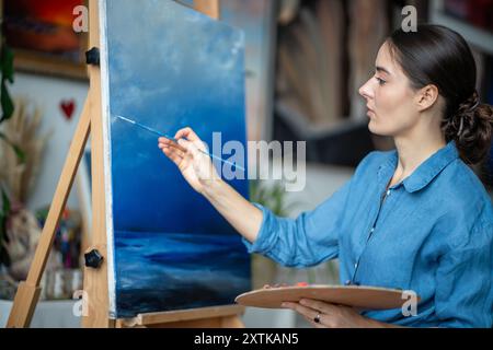 Eine inspirierte Künstlerin kreiert Ozeanmalerei mit Ölfarben im Studio. Meisterkurs an der Kunstschule. Stockfoto