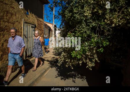 15. August 2024, Calzada Del Coto, Castilla Y Leon, Spanien: Die Nachbarn laufen an einem Wagen voller Brennholz entlang, während ein Traktor durch die Straßen von Calzada del Coto fährt, während der Vorbereitungen für die Feier des Lagerfeuers von San Roque. Die Stadt Calzada del Coto feiert das Lagerfeuer von San Roque, eine Tradition, die mehr als siebzig Jahre alt ist. Es besteht darin, dass die Ältesten am Morgen des 15. August auf den Berg gehen, um Eichenfeuer zu sammeln und einen Wagen zu füllen, der von einem Traktor gezogen wird, um mit einer großen Party in die Stadt zu kommen und Vorbereitungen für das große Lagerfeuer von San Roque zu treffen Stockfoto