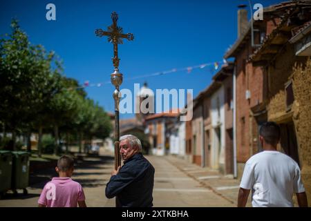 15. August 2024, Calzada Del Coto, Castilla Y Leon, Spanien: Ein Mann trägt ein Kreuz während der Prozession des Bildes San Roque durch die Straßen von Calzada del Coto, während der Vorbereitungen für die Feier des Lagerfeuers von San Roque. Die Stadt Calzada del Coto feiert das Lagerfeuer von San Roque, eine Tradition, die mehr als siebzig Jahre alt ist. Es besteht darin, dass die Ältesten am 15. August morgens auf den Berg gehen, um Eichenfeuer zu sammeln und einen Wagen zu füllen, der von einem Traktor gezogen wird, um mit einer großen Party in die Stadt zu kommen und Vorbereitungen für das große Lagerfeuer von San Roque tha zu treffen Stockfoto