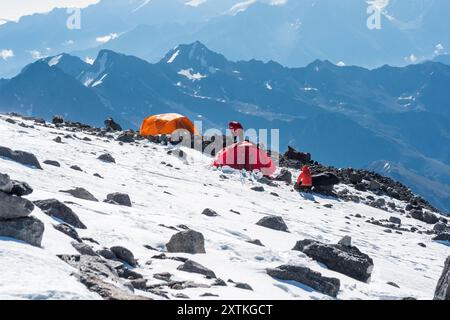 Elbrus, Russland - 2. August 2024: Hochgebirgslandschaft mit Bergsteigen zwischen ewigem Schnee und Felsen Stockfoto