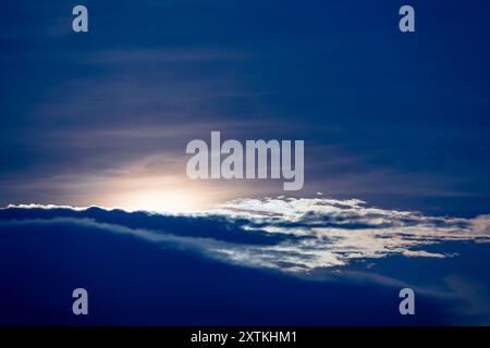 Nachts steigt der Mond langsam über Turtle Island auf, wo er plötzlich von Wolken verdeckt und dann dem ruhigen Wasser des Pazifischen Ozeans ausgesetzt wird. Stockfoto