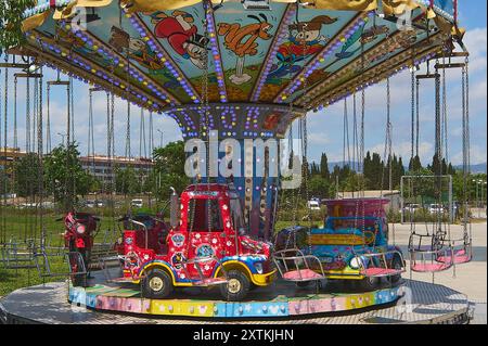 Viladecasn, SPANIEN - 15. AUGUST 2024: Buntes Kinderkarussell mit Fahrzeugen und hängenden Sitzen unter einem mit Cartoon verzierten Baldachin Stockfoto